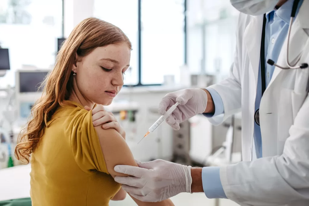 Doctor injecting HPV vaccine into teenage girl arm