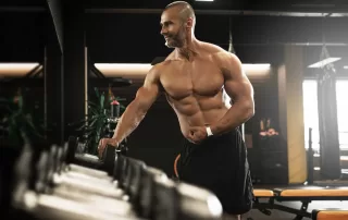 Muscular bodybuilder suffering from bigorexia checking himself in the mirror at the gym