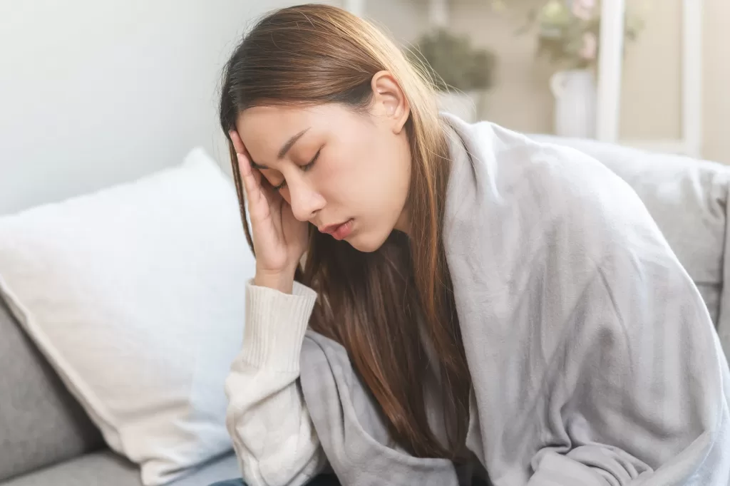 Woman with dengue touches her forehead having a headache and fever