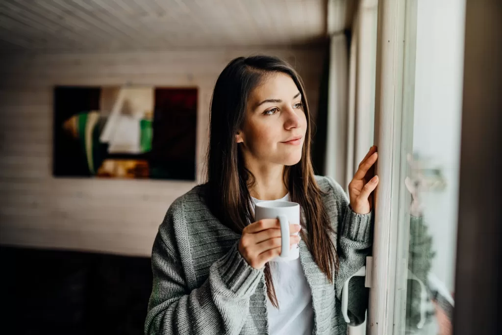 Young woman gazing through to the window avoiding social contact